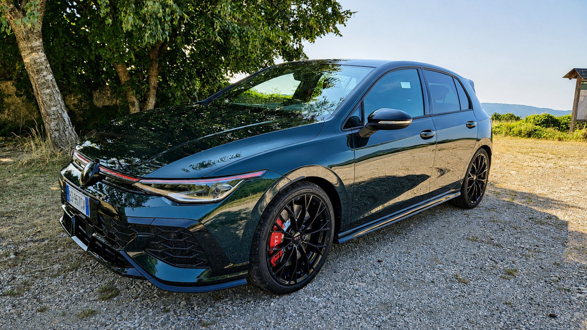 Una Volkswagen Golf GTI Edition 50 rossa parcheggiata su strada con logo celebrativo, dettagli sportivi in primo piano